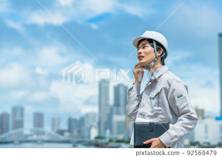A young engineer wearing a helmet that works outdoors 92568479