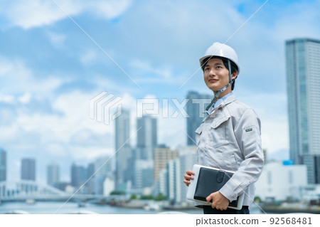 A young engineer wearing a helmet working outdoors A young engineer wearing a helmet working outdoors 92568481