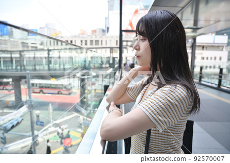 A woman looking at the scenery from the second floor of the sidewalk A woman looking at the scenery from the second floor of the sidewalk 92570007