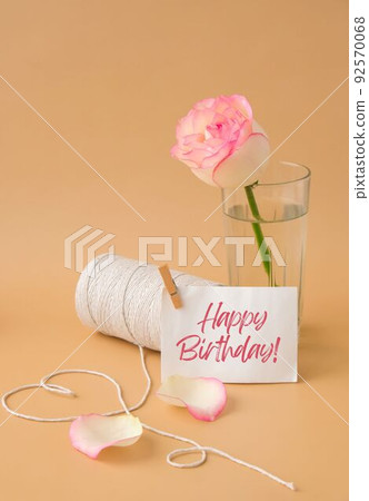 HAPPY BIRTHDAY text Tender pink roses with spool of white cotton rope in heart shape on beige background. Romantic pastel pink rose flowers. Neutral earth tones. Greeting card 92570068