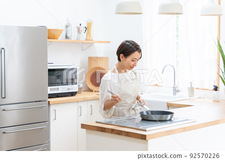 A smiling middle-aged woman cooking in the kitchen (housework, housework, self-catering) A smiling middle-aged woman cooking in the kitchen (housework, housework, self-catering) 92570226