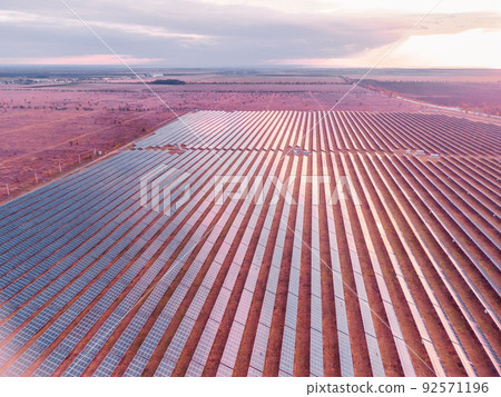 Aerial top view of a solar panels power plant. Photovoltaic solar panels at sunrise and sunset in countryside from above. Modern technology, climate care, earth saving, renewable energy concept. 92571196