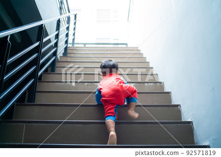 Funny baby boy crawling climbs up stair 92571819