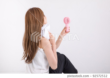 Woman wiping sweat with a towel 92572512