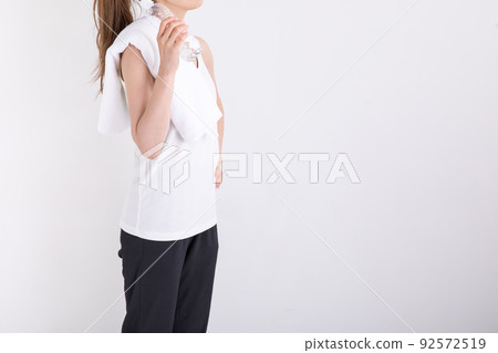 A woman who rehydrates with a plastic bottle in one hand 92572519