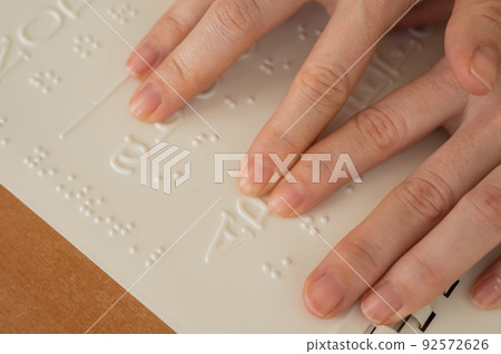 A woman learns the Braille alphabet using a decoder. 92572626