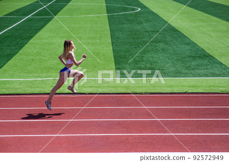 Young caucasian woman is engaged in jogging at the stadium outdoors. 92572949
