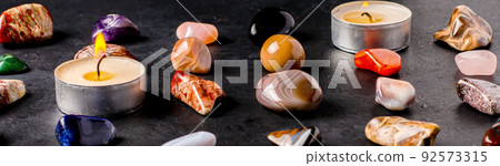 Mineral stones and candles on a black concrete background. The concept of using minerals in astrology and alternative or complementary medicine. 92573315