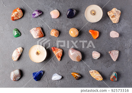 Mineral stones and candles on a black concrete background. The concept of using minerals in astrology and alternative or complementary medicine. Mineral stones and candles on a black concrete background. The concept of using minerals in astrology and alternative or complementary medicine. 92573316