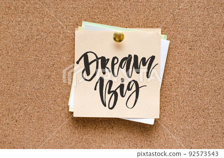 Paper notes with handwritten motivational inscriptions are pinned to a cork board. Paper notes with handwritten motivational inscriptions are pinned to a cork board. 92573543