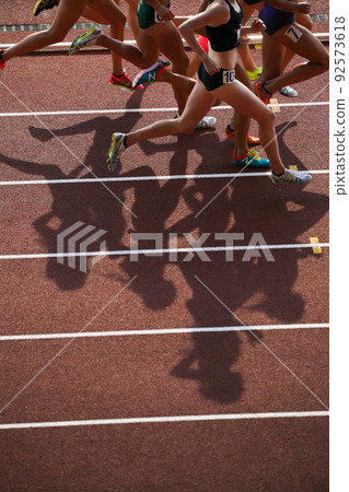 Shadow of a female athlete running on an athletics stadium 92573618