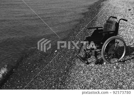 An empty wheelchair on a rocky seashore. An empty wheelchair on a rocky seashore. 92573780