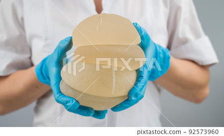The plastic surgeon holds breast silicone implants. The plastic surgeon holds breast silicone implants. 92573960