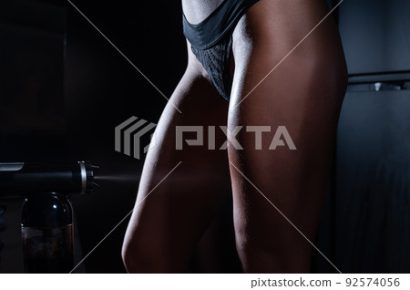 The master applies tinting paint to the woman's legs. Instant tanning procedure 92574056