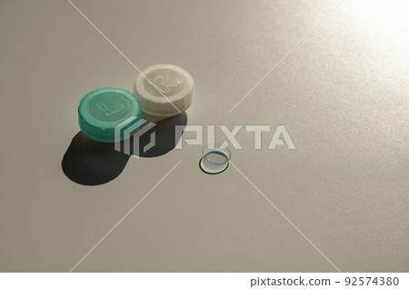 Contact lenses and a storage container on a white table. Contact lenses and a storage container on a white table. 92574380