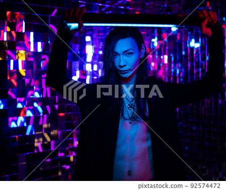 Portrait of a transgender model with a naked torso in a studio with neon lighting. 92574472