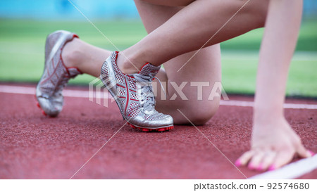 Close-up of female legs. The runner in the stadium is ready for the race. 92574680