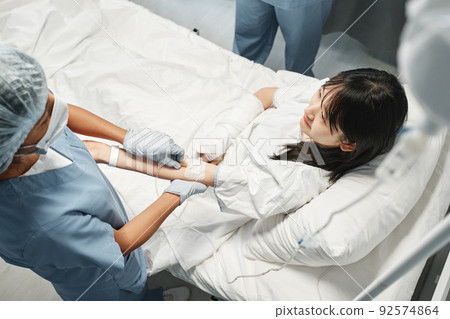 Horizontal high angle view shot of young Asian woman getting intravenous therapy in emergency room 92574864