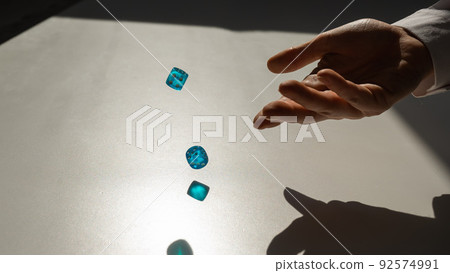 Woman throws a pair of blue transparent dice.  92574991