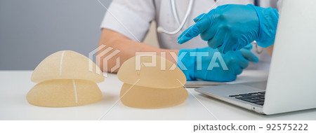 Doctor plastic surgeon explains the benefits of different breast implants. Doctor plastic surgeon explains the benefits of different breast implants. 92575222