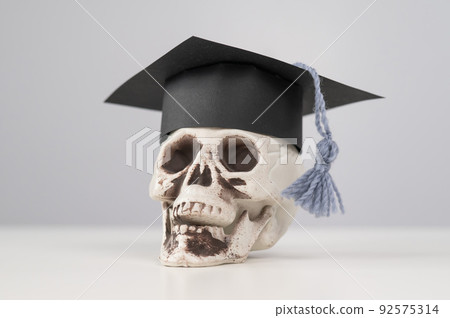 Toy plastic skull with academic cap on a white background. Toy plastic skull with academic cap on a white background. 92575314