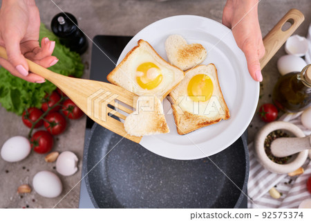 Fried egg Toasts with heart shaped holes on frying pan 92575374