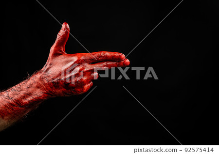 Bloody male hand gesturing shows a gun against black background. Bloody male hand gesturing shows a gun against black background. 92575414