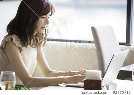 Middle-aged woman working on a computer at a restaurant 92575712