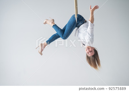 Caucasian woman in casual clothes on an aerial hoop. Caucasian woman in casual clothes on an aerial hoop. 92575889