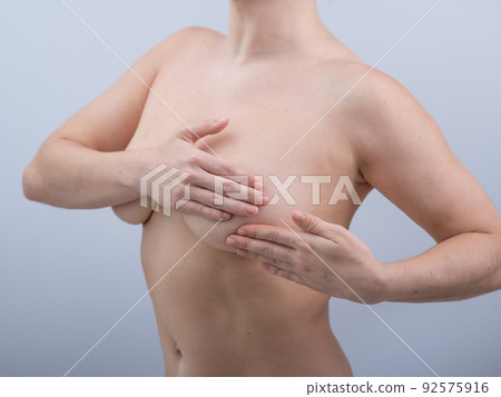Caucasian woman self checks for breast cancer on white background. Caucasian woman self checks for breast cancer on white background. 92575916