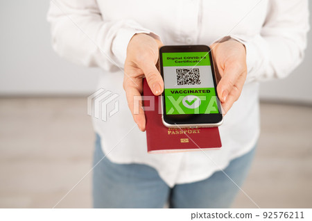 Woman holding passport and phone with qr code about vaccination. Woman holding passport and phone with qr code about vaccination. 92576211