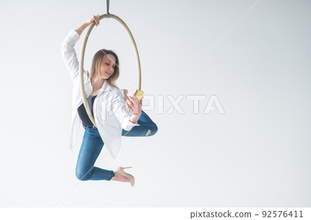 Caucasian woman gymnast on an aerial hoop takes a selfie on a smartphone.  92576411