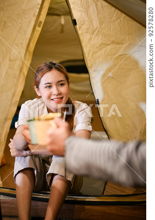 Happy Asian friends camping and relaxing together, enjoy talking and having a hot drink at night. 92578280
