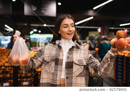 Eco friendly woman buys apples in the supermarket. Female grocery shopper opposes the use of plastic bags 92579091
