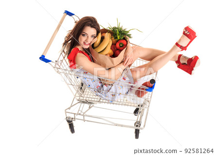 High angle view of girl smiling at camera while holding grocery bags and sitting in shopping trolley isolated on white High angle view of girl smiling at camera while holding grocery bags and sitting in shopping trolley isolated on white 92581264