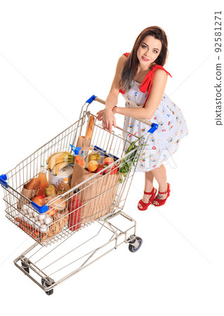 High angle view of girl smiling at camera while pushing a shopping cart full with groceries isolated on white background. High angle view of girl smiling at camera while pushing a shopping cart full with groceries isolated on white background. 92581271