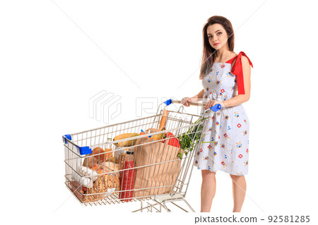 A young female pushing a shopping cart full with groceries isolated on white background A young female pushing a shopping cart full with groceries isolated on white background 92581285