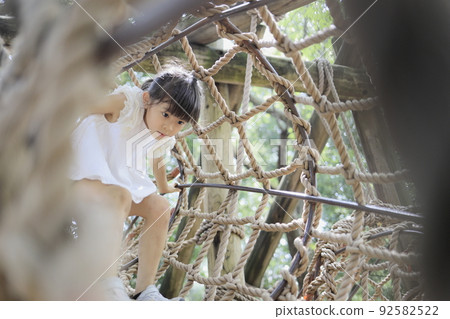 Elementary school girl playing on a tightrope (7 years old) Elementary school girl playing on a tightrope (7 years old) 92582522