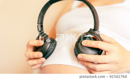 Baby music pregnancy woman. Cheerful pregnant girl relaxing listening music in headphones. Mother belly listen headphones sound. Therapy, healthcare, motherhood concept. Baby music pregnancy woman. Cheerful pregnant girl relaxing listening music in headphones. Mother belly listen headphones sound. Therapy, healthcare, motherhood concept. 92582768