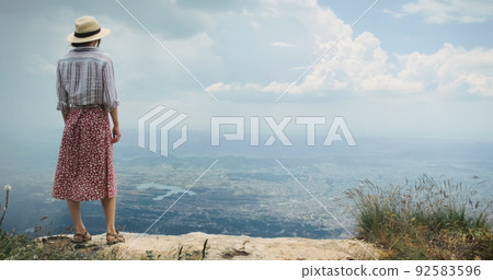 Woman traveler on mountain top lookig at city from height of flying flight. Epic concept of achievement, travel, opening up new horizons, experiences. Tirana city view from mountain Dajti, Albania 92583596