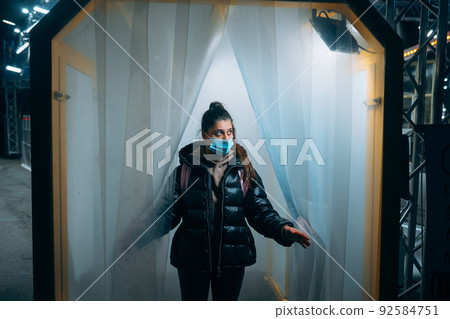 Woman at medic mask is staying in a disinfection tunnel 92584751