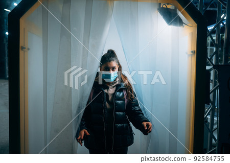 Woman at medic mask is staying in a disinfection tunnel Woman at medic mask is staying in a disinfection tunnel 92584755