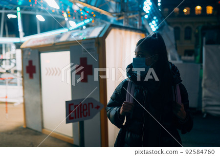 Woman in a medic mask is staying at disinfection tunnel Woman in a medic mask is staying at disinfection tunnel 92584760