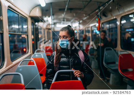 Young woman with mask traveling in the public transport. 92584763