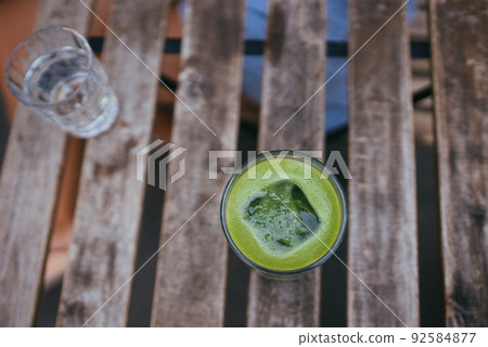 Iced green matcha latte tea on wooden table Iced green matcha latte tea on wooden table 92584877