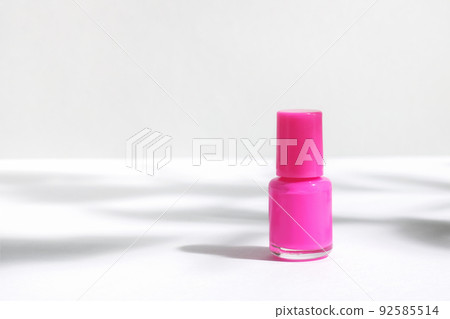 Creative mockup of isolated cosmetic bottle with pink nail polish, on white background with hard shadows from plants. The concept of nail care, manicure or pedicure. Beauty salon advertisement. 92585514