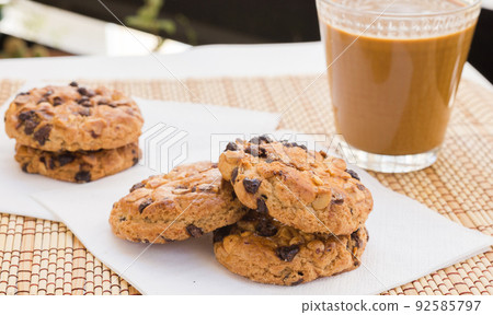 cookies with chocolate and hazelnuts and coffee with milk lie on the table cookies with chocolate and hazelnuts and coffee with milk lie on the table 92585797