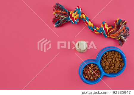 Toys -multi coloured rope, ball and dry food. Accessories for play on pink background top view Toys -multi coloured rope, ball and dry food. Accessories for play on pink background top view 92585947