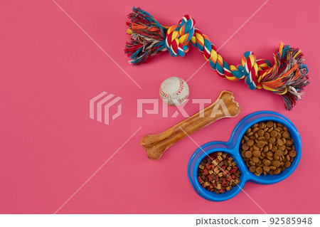 Toys -multi coloured rope, ball, dry food and bone. Accessories for play on pink background top view 92585948