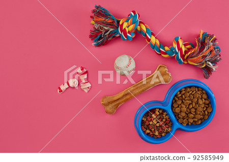 Toys -multi coloured rope, ball, dry food and bone. Accessories for play on pink background top view Toys -multi coloured rope, ball, dry food and bone. Accessories for play on pink background top view 92585949